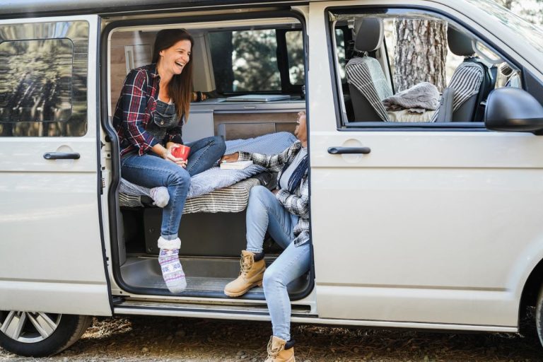 Un jeune couple qui discute et ris dans leur camping-car
