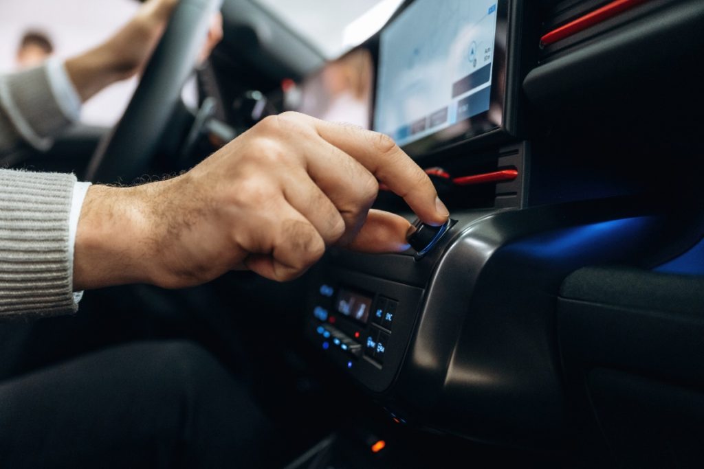 Main d'un homme augmentant le volume sur le système audio de sa voiture