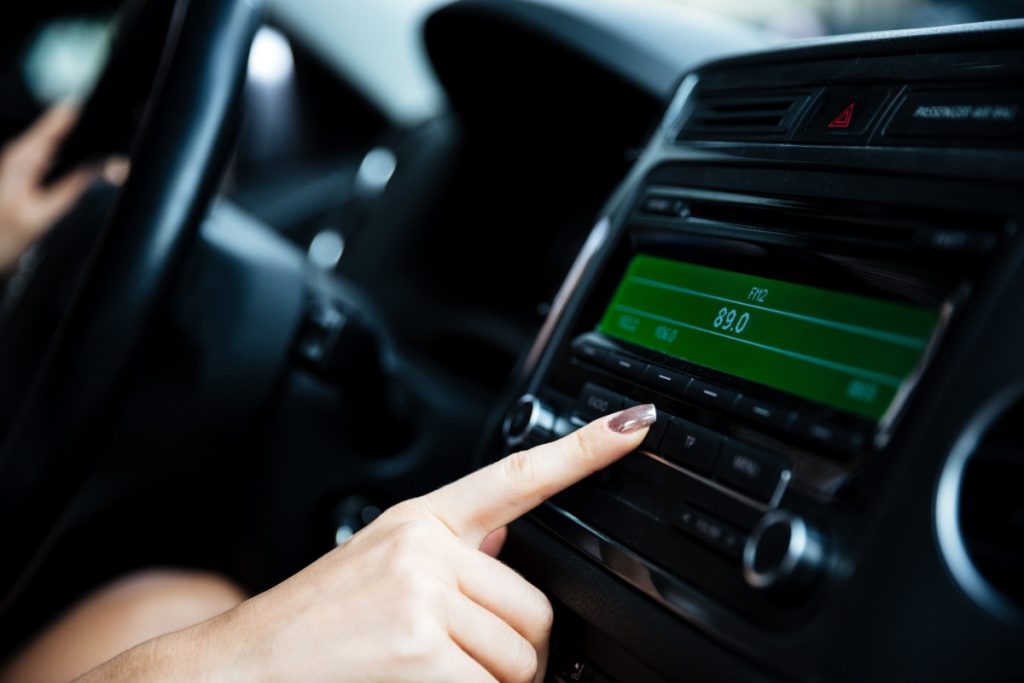 Main d'une femme posée sur l'auto radio de sa voiture