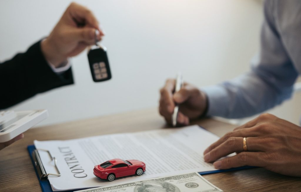 Une personne qui signe les papiers pour l'achat d'une voiture