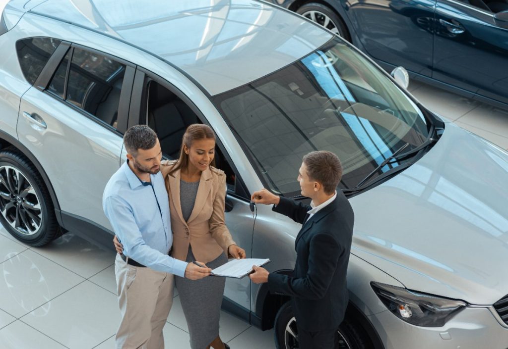Un homme qui vend sa voiture à un jeune couple