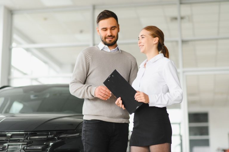 Un homme discutant avec une vendeuse de voiture d'occasion dans un garage