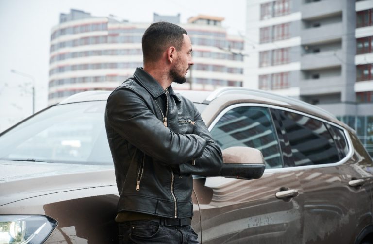 Un homme appuyé sur sa voiture