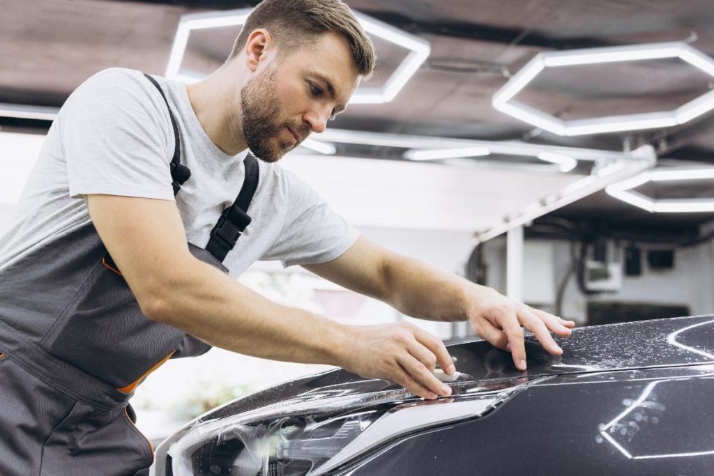Un homme mettant du film de détail protection pour peinture de la voiture