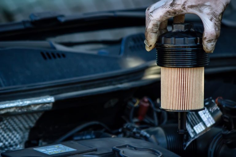 Main avec un gant qui remplace le filtre à huile d'une voiture