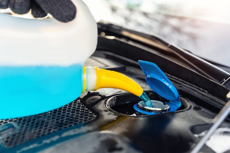 Une personne qui ajoute du liquide de refroidissement dans la voiture