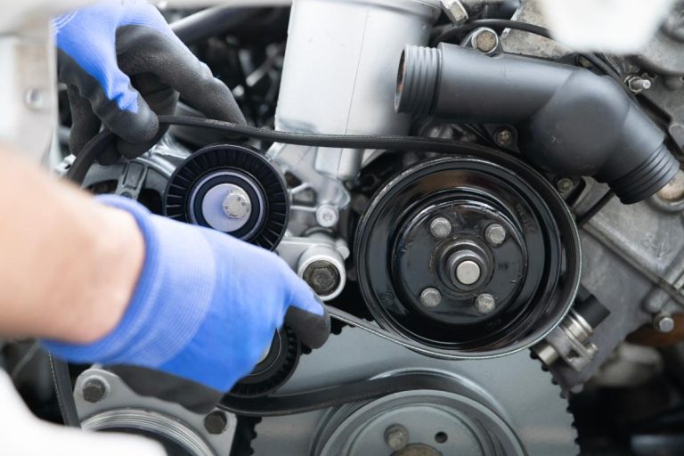 Une personne faisant un entretien d'une courroie moteur