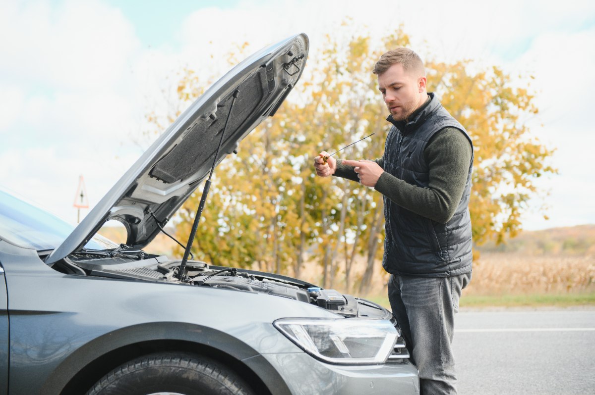 Un homme inspectant le moteur de son véhicule au bord de la route