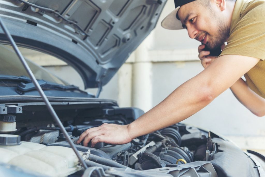 Un homme réparant la voiture et parlant au téléphone