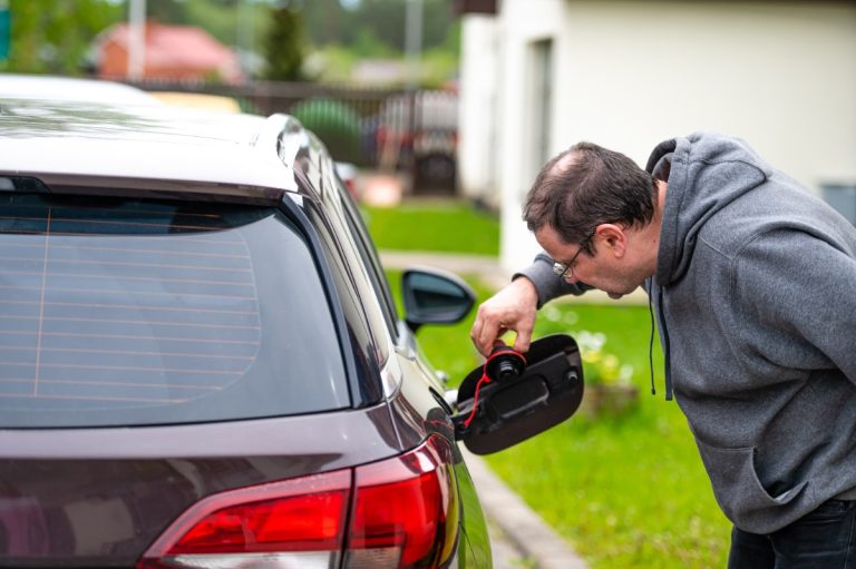 Un homme vérifiant le réservoir du carburant de sa voiture