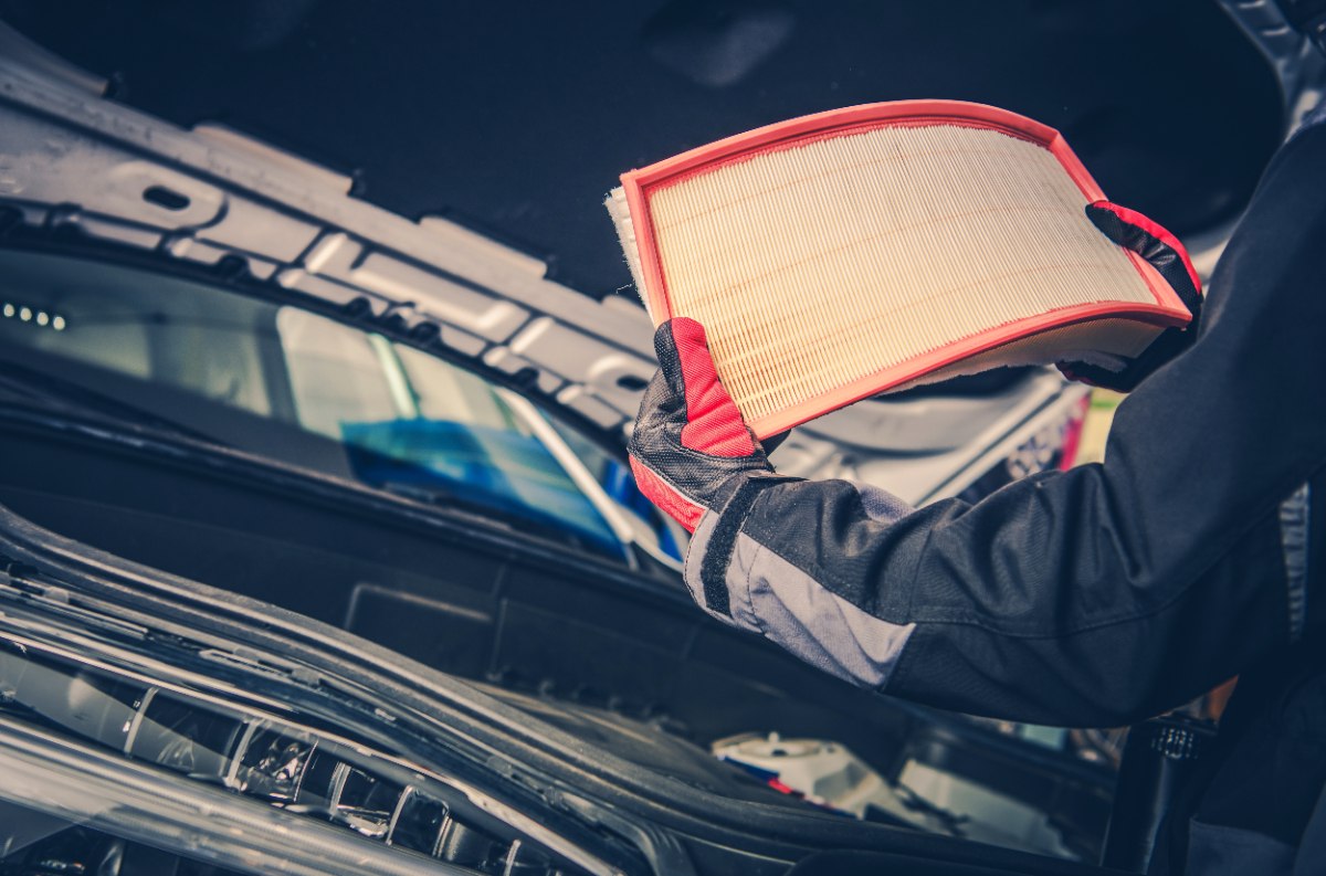Une personne qui remplace le filtre à air de sa voiture